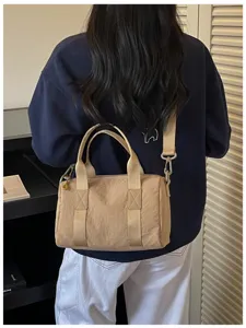 Close-up detail of a casual beige cylindrical shoulder bag worn by a model, lifestyle view.