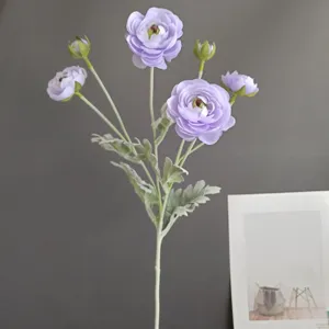 Close-up detail view of artificial purple ranunculus flower branch with realistic green leaves and buds.