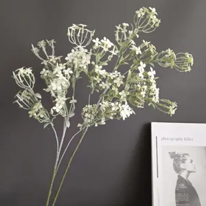 Gros plan détail de branche de lilas artificiel, fleurs blanches et tige verte pour déco maison.
