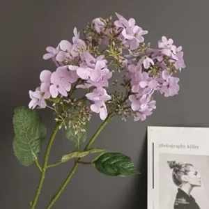 Vista detallada de una rama de flor de hortensia morada artificial con hojas verdes decorativas.