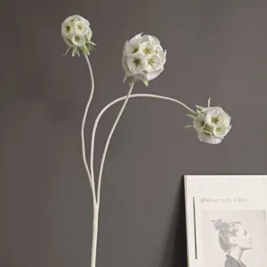 Gros plan détaillé d'une branche de fleur artificielle floquée avec des fleurs blanches.