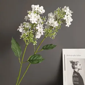 Primer plano detallado de una rama de flores blancas artificiales con hojas verdes para hogar.