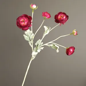 Close-up view of artificial red ranunculus flower branch with delicate petals and green leaves.