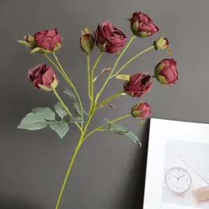 Artificial rose flower detail closeup, dark red burgundy floral branch decor for home.