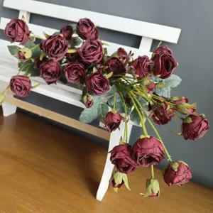 Detailed shot of dark red artificial roses bouquet placed on a white wooden bench for home decor.