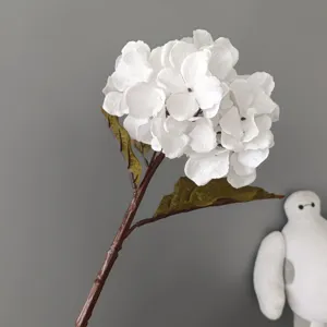 Primo piano dettagliato di uno stelo di ortensia bianca artificiale con foglie realistiche.