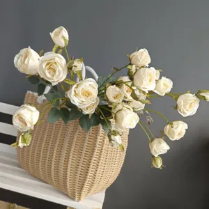 Artificial cream roses in woven basket Nordic floral decor detail shot for home interior.