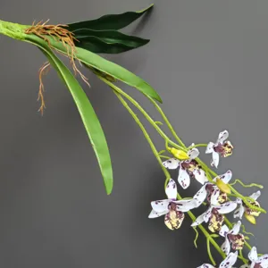 Primo piano dettagliato del ramo di orchidea artificiale con foglie verdi e fiori realistici.