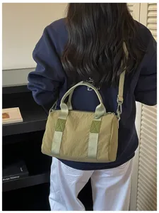 Detail view of a casual khaki barrel shoulder bag with sturdy webbed handles and strap.