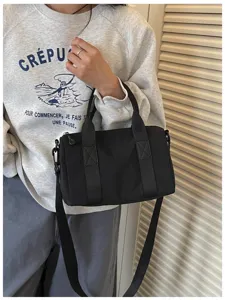 Detail view of the black canvas crossbody bag, featuring sturdy handles and strap.