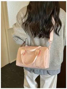 Casual pink nylon crossbody duffel bag worn on shoulder, daily commuting lifestyle view.