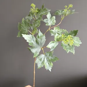 Rama de planta de hoja de uva artificial en detalle, follaje verde escarchado para decoración.