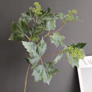 Detalle de rama de planta artificial, hojas de arce y vid falsas para decoración del hogar.