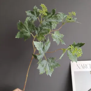 Vista detallada cercana de una rama de hojas verdes artificiales para decoración de interiores.
