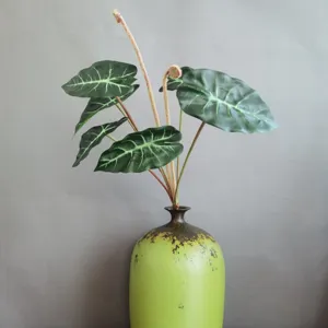 Ramo de plantas artificiales hojas oreja de elefante con jarrón de cerámica verde vintage