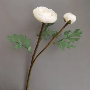 Closeup detail of artificial white ranunculus flower with green leaves and realistic stem.