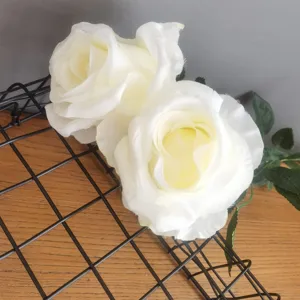Gros plan de roses artificielles blanches en soie sur grille métallique pour déco florale.