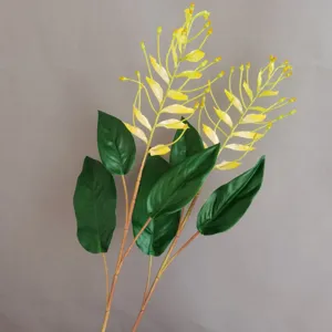 Künstliche Blumen Detailaufnahme mit gelbem Orchideenzweig und grünen Blättern für Deko.