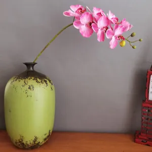 Künstliche Schmetterlingsorchidee Blüte in rustikaler grüner Keramikvase für Heimdekoration