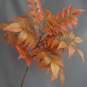 Detalle de rama de hojas de otoño artificiales, follaje naranja realista para decoración.