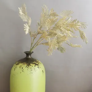 Artificial fern leaves branch with vintage green ceramic vase for nordic home decor detail.