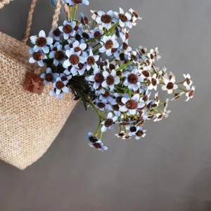 Detail shot of artificial daisy flowers with fuzzy centers in a woven bag for home decor.