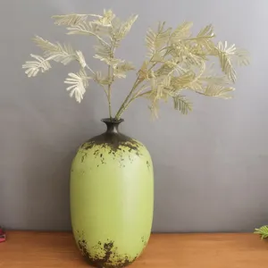 Nordic style green ceramic vase with golden artificial fern branches for home decor and wedding.