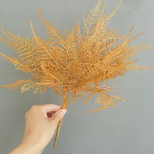 Primer plano detallado de rama de helecho artificial, ideal para decoración del hogar.