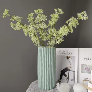 Primer plano de ramas de bayas verdes artificiales en un jarrón elegante para decoración.