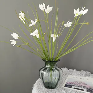 Artificial white flower bouquet with green glass vase detail shot for home decor.