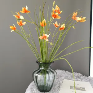 Artificial orange flower arrangement in dark glass vase for home decor and interior design styling.