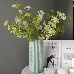 Ramas de fruta artificiales con florero de cerámica, detalle de arreglo floral decorativo.
