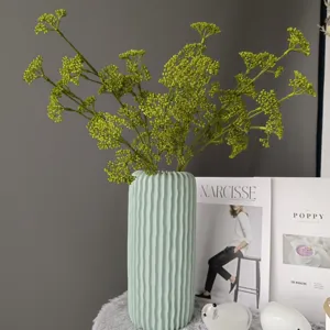 Rama de bayas verdes artificiales en florero de cerámica acanalado para decoración de hogar