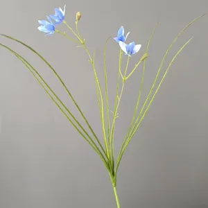 Detail view of artificial blue rain lily flower stem with long green grass leaves for decor.