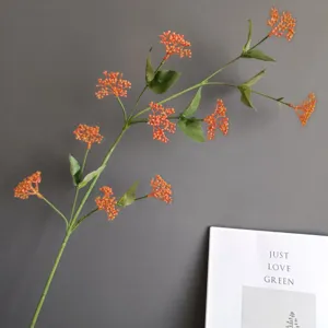 Detailaufnahme künstlicher orangefarbener Beerenzweig mit grünen Blättern für Inneneinrichtung.