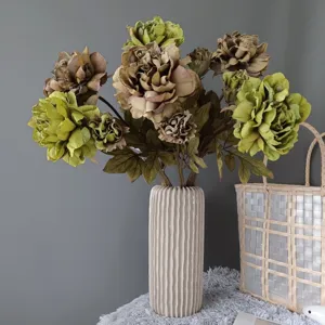 Primo piano dettagliato di un bouquet di peonie artificiali retrò in vaso di ceramica bianca.