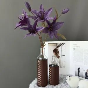 Artificial purple lily flowers in leather wrapped glass vase home decor arrangement detailed view.