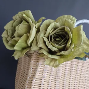 Primer plano detallado de rosas artificiales vintage verdes en una cesta tejida decorativa.