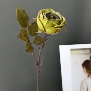 Primer plano de la cabeza de rosa artificial retro y la rama de hojas texturadas vintage
