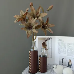 Artificial lily flower arrangement in glass vase with leather wrap for home decor and weddings.