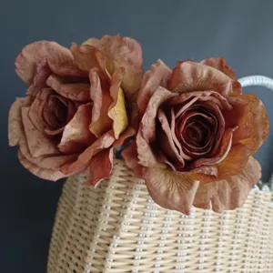 Primer plano detallado de rosas artificiales vintage con bordes quemados en cesta.