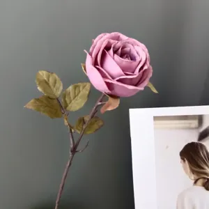 Primer plano detalle de flor de rosa rosa retro artificial con tallo y hojas para decoración del hogar.