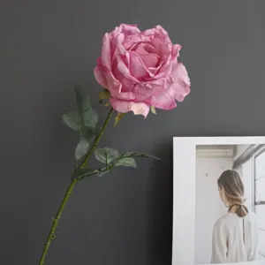 Vista de cerca detallada de una sola rosa artificial rosa vintage con hojas muy realistas.