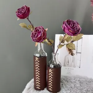 Primer plano de rosas artificiales en jarrones de cristal con fundas de cuero, decoración.