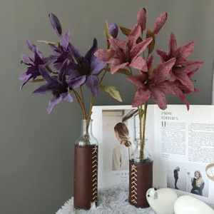 Closeup of artificial lily flower detail with leather wrapped glass vase in home decor scene.