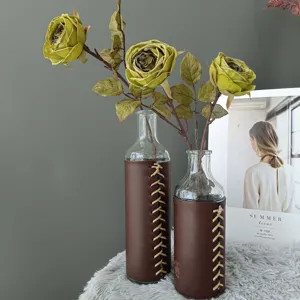 Set de floreros de vidrio decorativos con fundas de cuero marrón y rosas verdes artificiales.