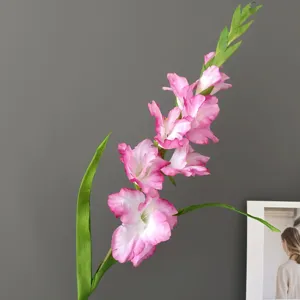 Artificial Gladiolus flower detail shot, pink and white gradient petals with green leaves.