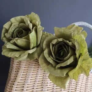 Primer plano detalle de rosas artificiales verdes vintage con bordes quemados en canasta.