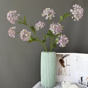 Vista detallada de un ramo de flores de hortensia artificial en un florero acanalado verde menta