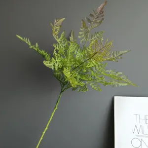 Artificial fern branch detail shot, plastic green leaf stem for home decor and floral design.